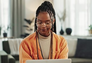 Black woman, typing in home office and laptop for remote work, social media or blog research in apartment. Freelance girl at desk with computer writing email, website post and online chat in house.